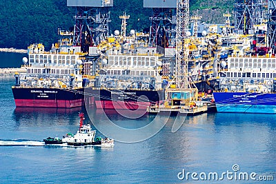 Tugboat sails pass driil ships in the Bay of Daewoo Shipbuilding and Marine Engineering DSME in Okpo city, South Korea. Editorial Stock Photo