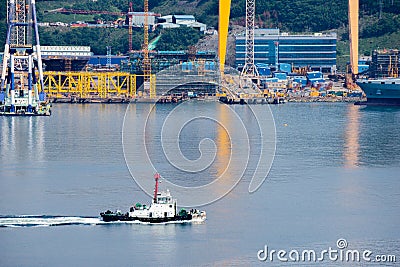 Tugboat sails pass driil ships in the Bay of Daewoo Shipbuilding and Marine Engineering DSME in Okpo city, South Korea. Editorial Stock Photo