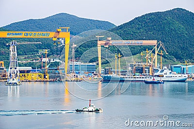 Tugboat sails pass Tideforce UK`s replenishment vessel in the Bay of Daewoo Shipbuilding and Marine Engineering DSME in Okpo Editorial Stock Photo