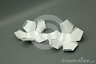 Geometric shape cut out of paper and photographed on grey background.Dodecahedron. 2d shape foldable to form a 3d shape or a solid Stock Photo