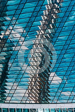 Geometry and lines of a modern business center. Clouds and buildings are reflected in the glass windows of the high-rise Stock Photo