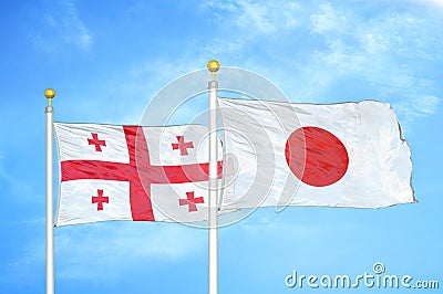 Georgia and Japan two flags on flagpoles and blue sky Stock Photo