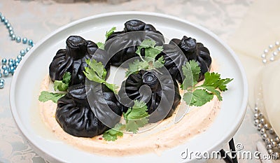 Georgian khinkali made from black dough with coriander and spicy sauce. Restaurant serving Stock Photo