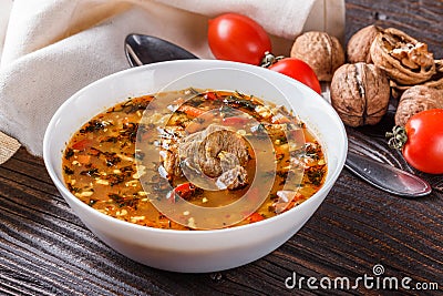 Georgian soup. Kharcho with rice, tomato, beef, garlic and herbs in bowl on wooden table Stock Photo