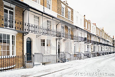 Georgian or Victorian style terrace houses other wise known as row houses in the snow in winter. They have ornate railings and Stock Photo