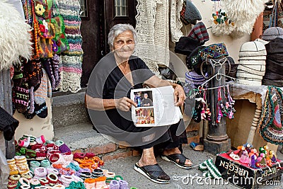 Georgian woman sits and sells on the street national rugs and knitted socks in Tbilisi. Georgia. Editorial Stock Photo