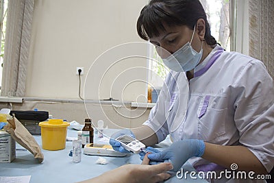 Geriatric nurse measures the blood sugar level Editorial Stock Photo