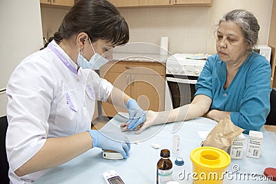 Geriatric nurse measures the blood sugar level Editorial Stock Photo