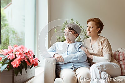 Geriatric woman and her professional caretaker sitting on a couc Stock Photo