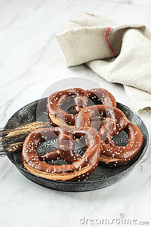 German Brezel Pretzel with Sesame Seed on Rustic Plate Stock Photo