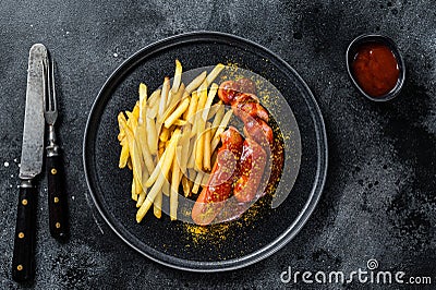 German currywurst Sausages with French fries on a plate. Black background. Top view Stock Photo