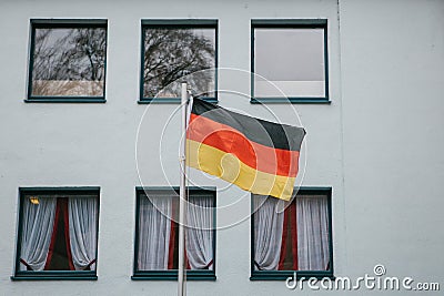 German flag on the outside of the building next to the windows. Patriotic sentiments before the elections. Stock Photo