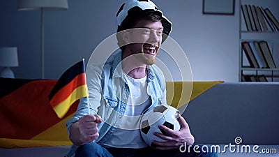 German football fan enthusiastic watching game on sofa, supporting national team Stock Photo