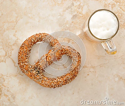 German pretzel sprinkled with seeds and a mug of beer on the mar Stock Photo