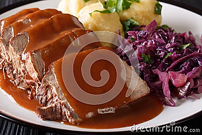 German roast pot Sauerbraten served with potato dumplings and re Stock Photo