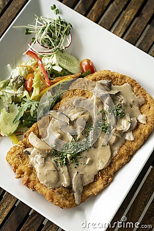 German veal Jagerschnitzel schnitzel cutlet with mushroom sauce and salad Stock Photo