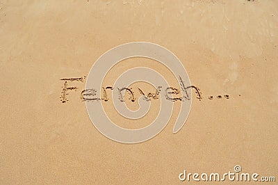 German word 'Fernweh' in the sand Stock Photo