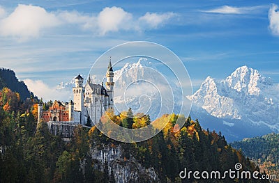 Germany. The famous Neuschwanstein Castle in the background of snowy mountains and trees with yellow and green leaves. Stock Photo