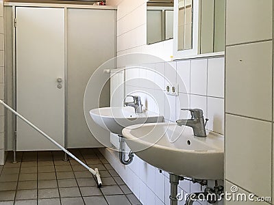 GERMANY - MAY 2016: Interior of an old bathroom. White washbasins, doors. Editorial Stock Photo