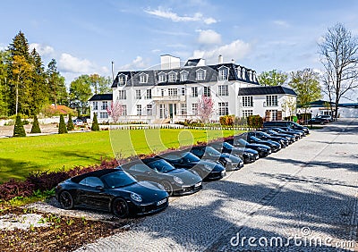 Germany, Munich, 26 April 2019: Aerial video of the group of black sports cars are before the white building of hotel in a sunny Editorial Stock Photo