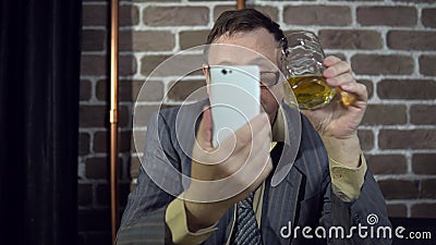 Geschäftsmann unter Verwendung des Telefons und des trinkenden Alkohols zuhause mit Backsteinmauer stock video footage Geschäftsmann unter Verwendung des Telefons und des trinkenden Alkohols zuhause mit Backsteinmauer stock video footage