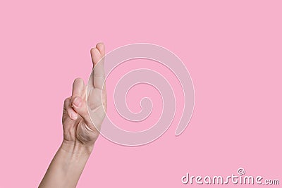Gesture symbol of good luck, fingers crossed, bright hand on a pink background. Stock Photo