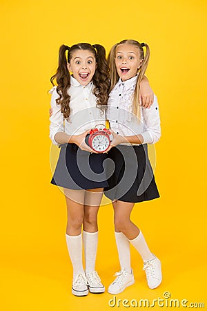 Getting back to class in time. Happy little girls back to school on september 1. Small schoolchildren smiling with clock Stock Photo