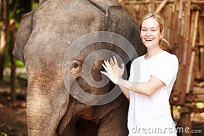 Getting close - Thailand. Portrait of a young eco-tourist gently petting a young Asian elephant. Stock Photo