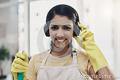 Getting into the domestic goddess groove. a young woman listening to music while cleaning her home. Stock Photo