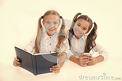 Getting information. Modern data storage instead big paper book. Little girls read paper book and ebook smartphone Stock Photo