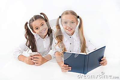 Getting information. Modern data storage instead big paper book. Little girls read paper book and ebook smartphone Stock Photo