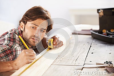 Getting the measurements right. A handsome young carpenter measuring and marking wood. Stock Photo