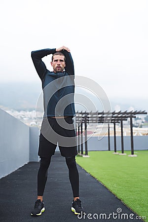 Getting ready to go harder, longer and faster than before. a sporty young man stretching while exercising outdoors. Stock Photo