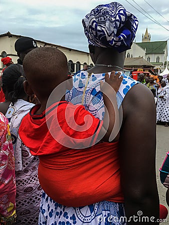 Ghana. The people. A young mother carrying her baby with a red t-shirt at the Fetu Afahye festival in Cape Coast Editorial Stock Photo