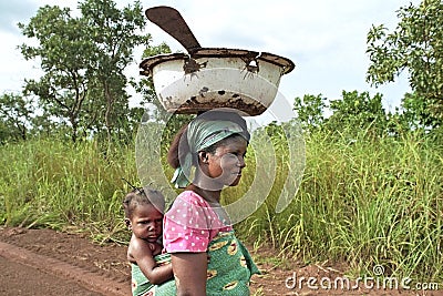 Ghanaian Woman lugging child and kitchen utensils Editorial Stock Photo