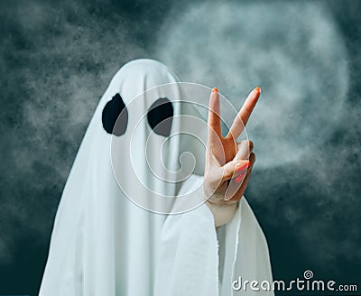 Ghost showing peace gesture in Halloween full moon night. Stock Photo