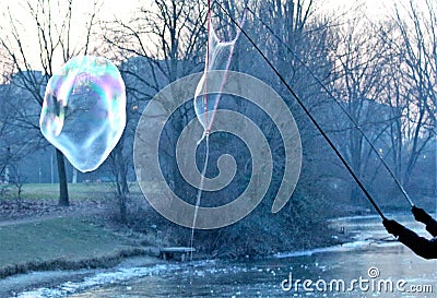 A giant bubble floating free in the open and another that is forming Stock Photo