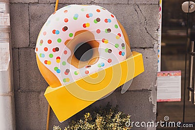 Giant donut sign in front of cafe or restaurant with empty copy space for text or advertising. Fast food and sweet junk Stock Photo