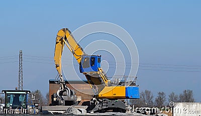 A giant excavator at work outside an industrial steel and cement area Stock Photo