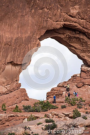 Tourists climb around in an arch inside of Arches National Park in Utah Editorial Stock Photo