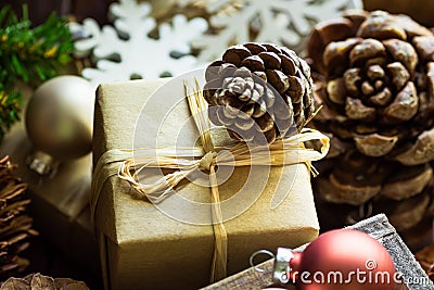 Gift box for Christmas and New Year wrapped in craft paper, pine cones, colorful balls, wood ornament snow flakes, rustic style Stock Photo