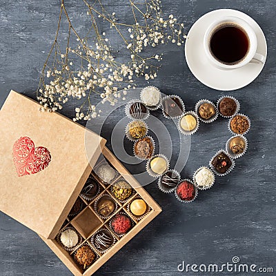 Gift box of gourmet chocolates for Valentine`s Day on dark background with cup of coffee, top view, copy space Stock Photo