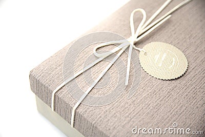 A gift box isolated over blue background with copy space. Box is tied with a cord with a label with Wishes and Happiness. Stock Photo