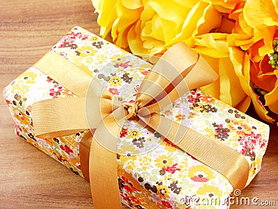 Gift box present and artificial flowers bouquet background yellow theme Stock Photo