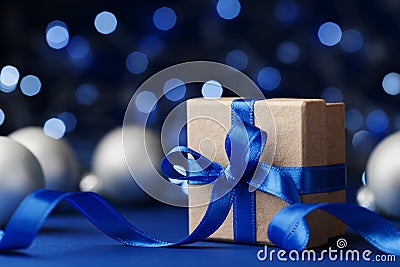 Gift box or present and christmas balls against blue bokeh background. Magic holiday greeting card. Stock Photo