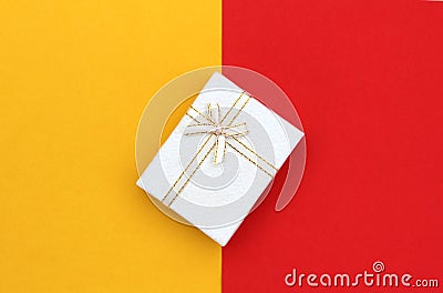 The gift box stands at the same time on the border of two colors, yellow and red. Stock Photo