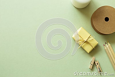 Gift box, string roll, wooden pencils, clips on green background Stock Photo