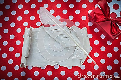 Gift box vintage paper roll feather on polka-dot red tablecloth Stock Photo