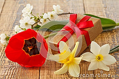 Gift box on wooden boards with flowers of daffodils, tulip and jasmine Stock Photo