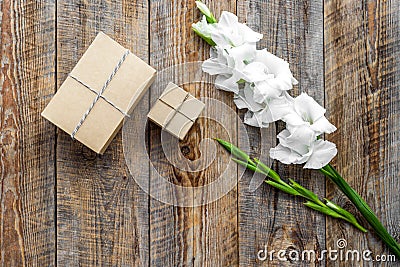 Gift box wrapped in craft paper near flower gladiolus on wooden background top view copyspace Stock Photo